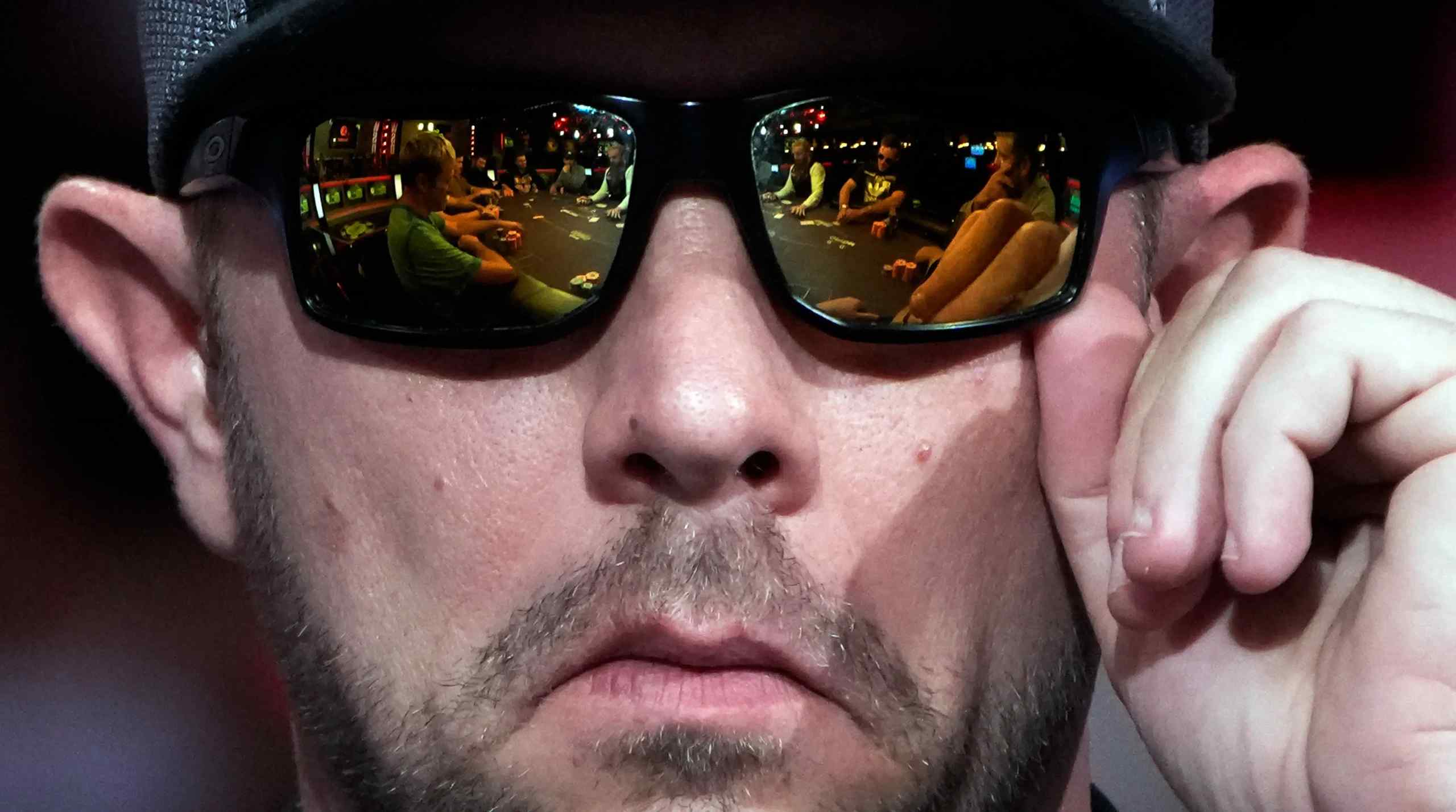 Poker player at WSOP in 2022. Reflection of the poker table on his sunglasses.